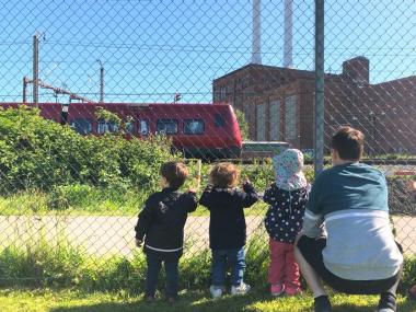 Børn og voksen kigger på tog